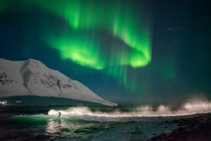Surfer rides the waves under the northern lights 