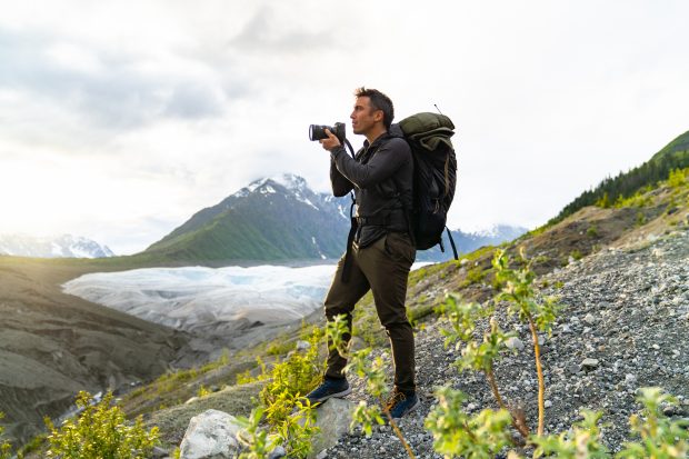 Chris Burkard standing on a mountain getting ready to take a photo with his camera